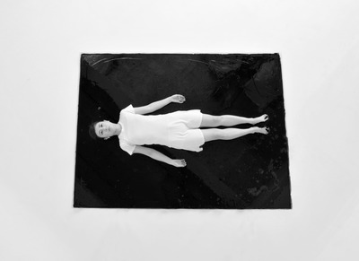 Lying in a pool of black paint, seen from above