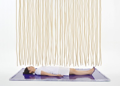 Lying on purple paint. Dozens of ropes hanging from above.