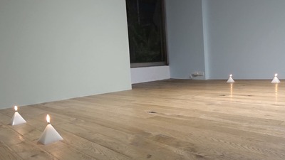 Four pyramid-shaped candles on the floor