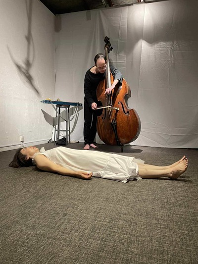 Tajima plays the contrabass, holding it from behind as if embracing it
