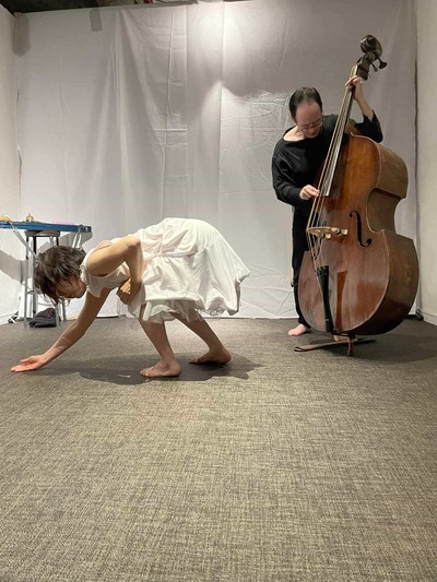 Ihoda in a half-squat with both feet grounded; left hand crawling on the floor, right hand pressing the right knee