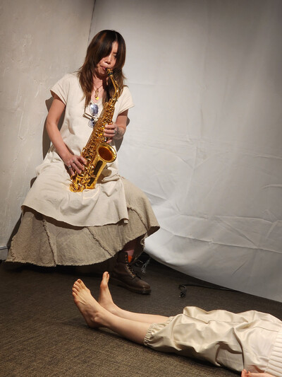 Koketsu wears an off-white dress with a light brown flared skirt underneath
