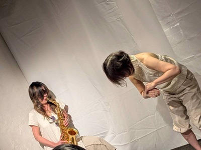Both with bangs over their faces; Ihoda is standing and bending forward.