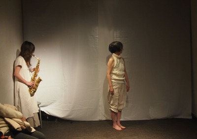 Koketsu stands leaning against the wall while playing; Ihoda stands looking upward