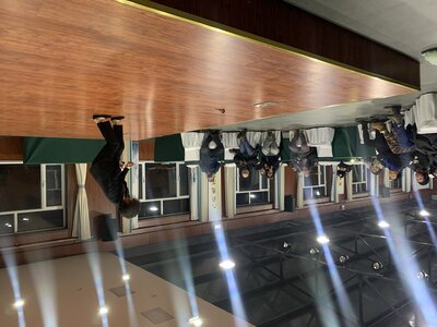Both feet press into the stage; the suited body approaches vertical, audience beyond
