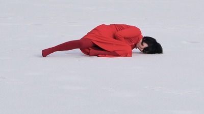 On the pure white ice, a bright red dress begins to move