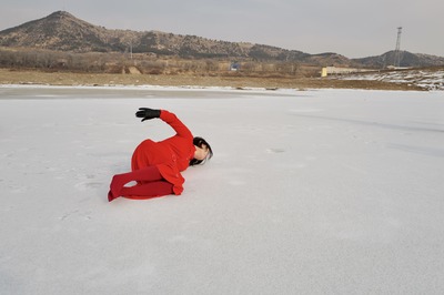 The left side of the body touches the ice; the right hand lifts, wearing a black leather glove