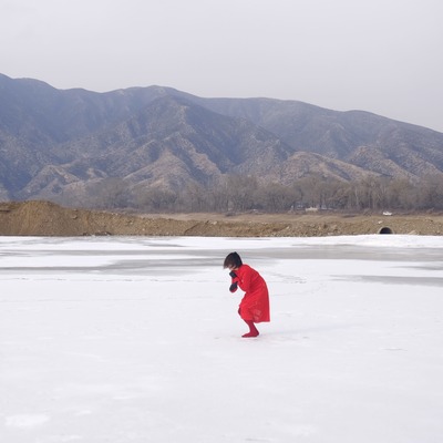 A small red form becoming vertical toward the sky; mountains in the distance