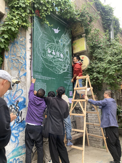 メイン会場のアートセンター外壁に巨大ポスター設置作業中
